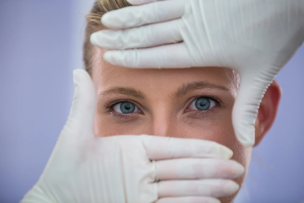 Médecin examinant le visage d'une patiente pour un traitement des cernes à l'acide hyaluronique.